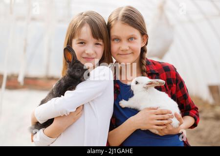 Due ragazze che tengono conigli nelle loro mani. Concetto di Pasqua Foto Stock