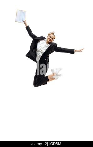Ritratto di giovane bella donna in nero abito ufficiale jumping in felicità isolato su sfondo bianco Foto Stock