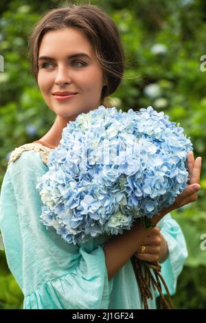 Giovane e bella donna fiorista collezione fiori Hydrangea Foto Stock