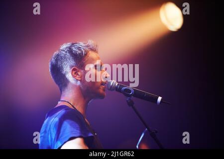 Girato di un musicista solitario che suona la chitarra e canta in un microfono. Questo concerto è stato creato per il solo scopo di questo scatto fotografico, in scena Foto Stock