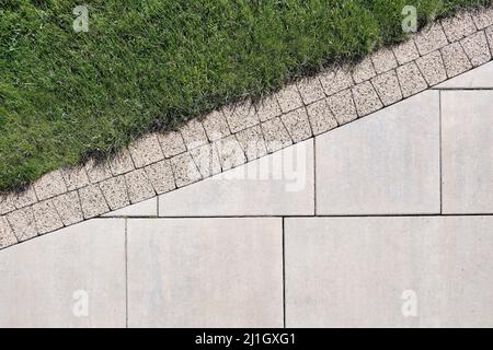 Combinazione di lastre di сoncrete e piastrelle di pavimentazione sul bordo con un prato, vista dall'alto. Foto Stock