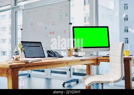 Pronto per iniziare a lavorare. Scatto di una scrivania non occupata con un computer e un tablet digitale all'interno di un ufficio durante il giorno. Foto Stock