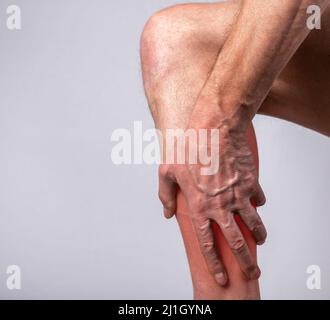 Dolore muscolare del vitello. Uomo mano che tiene gamba con punto rosso primo piano. Lesioni congiunte durante l'addestramento. Assistenza sanitaria, concetto di trattamento. Foto di alta qualità Foto Stock