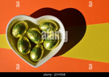 Cioccolatini a forma di cuore avvolti in lamina rossa e giallo oro su  sfondo bianco Foto stock - Alamy