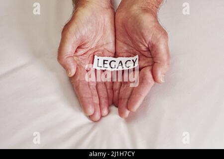 Che cosa è la vostra storia. Scatto ritagliato di una persona che tiene un pezzo di carta con la parola eredità scritta su di esso. Foto Stock