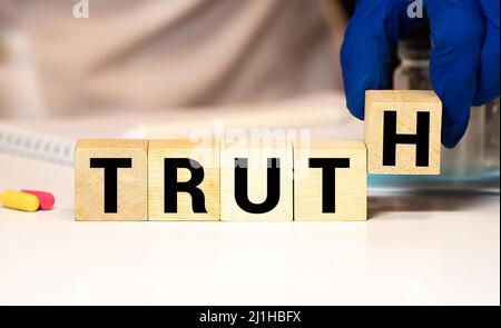 Verità - parola da blocchi di legno con lettere, fatti reali concetto di verità, lettere casuali intorno, sfondo bianco Foto Stock