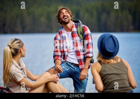 Gli amici si divertano nella natura. Giovani in escursione, ridendo e rilassandosi durante la pausa. Trekking, stile di vita, natura concetto Foto Stock
