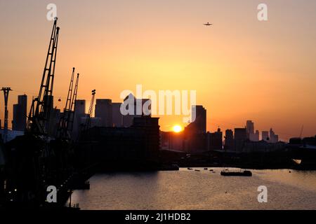 London, UK, 25th Mar, 2022. Un tramonto nebuloso sul Canary Wharf, con il bel tempo e il clima secco, continuerà per il resto del fine settimana, prima di cedere il passo a temperature più stagionali la prossima settimana. Dopo che questa settimana è stato lanciato un avvertimento sull'inquinamento atmosferico elevato per Londra, venerdì la qualità dell'aria è rimasta scadente in alcune parti della città. Credit: Undicesima ora Fotografia/Alamy Live News Foto Stock