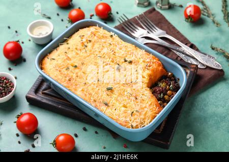 Piatto da forno con gustosa torta Shepherd su sfondo verde Foto Stock