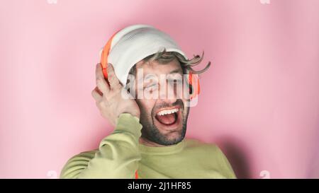 Giovane bell'uomo che indossa le cuffie e ascolta la sua canzone preferita, ballando, sorridendo a occhi chiusi Foto Stock