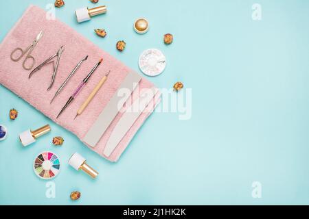 Un set di strumenti cosmetici per manicure e pedicure su sfondo blu. Lucidanti in gel, lime per unghie e tronchesini e vista dall'alto. Composizione per un cartoncino con Foto Stock