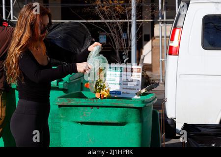 Una donna svuota gli scarti di cibo in un bidone di compostaggio a Union Square Greenmarket, New York. I rifiuti alimentari in questo luogo sono raccolti dal LES Ecology Foto Stock