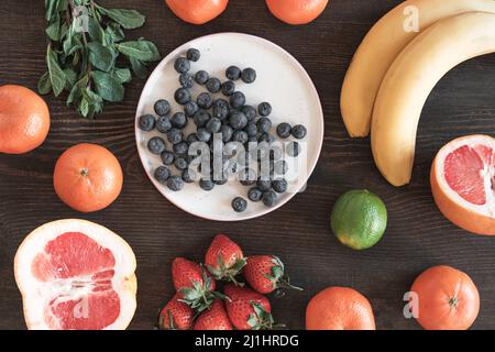 Direttamente sopra vista di deliziosi ingredienti come pompelmo, fragola, mirtillo e banane preparati per frullati di frutta Foto Stock