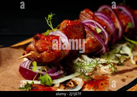 Kebab. Appetitose carni alla griglia con verdure ed erbe su sfondo di legno nero. Messa a fuoco soft. Primo piano Foto Stock