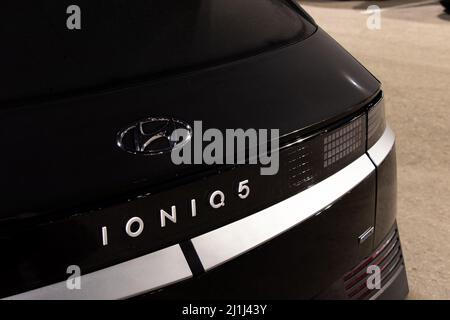 Un badge IONIQ 5, uno dei primi prodotti completamente elettrici di Hyundai venduti in tutto il mondo, è visto sul retro di un'auto nera di notte. Foto Stock