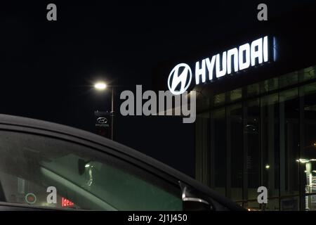 Un cartello Hyundai si illumina di notte in cima a una concessionaria di auto Hyundai. Foto Stock