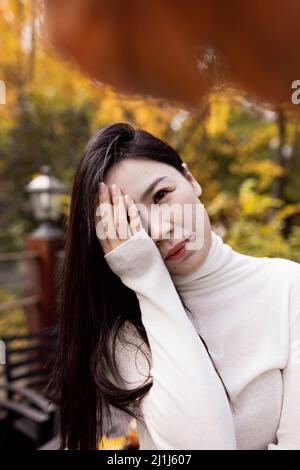 Triste donna asiatica stanca solitaria al bar all'aperto durante l'isolamento di auto quarantena per COVID-19 Coronavirus sociale prevenzione di allontanamento. Salute mentale Foto Stock