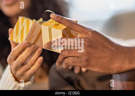 Una coppia felice di mulattini scambiano i regali l'uno con l'altro. Festeggiamo eventi familiari congiunti Foto Stock