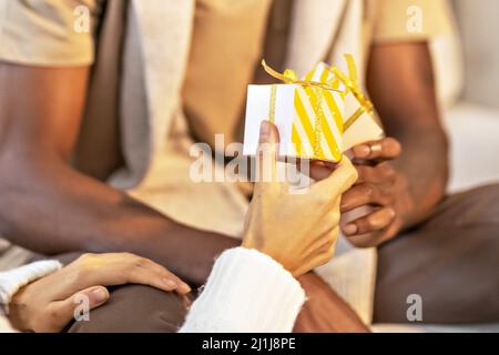 Una coppia felice di mulattini scambiano i regali l'uno con l'altro. Festeggiamo eventi familiari congiunti Foto Stock