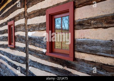 Parete esterna del paesaggio coloniale di capanna di legno riflessa nella finestra Foto Stock