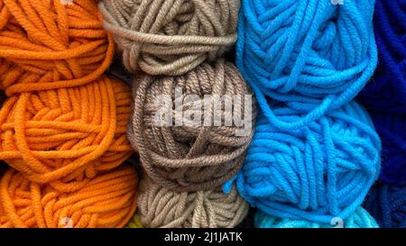 Gamma di filati di lana blu, arancione e marrone. Matasse multicolore di lana primo piano Foto Stock