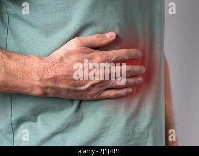 Dolore al fegato. Mano dell'uomo che tiene l'addome lato destro con punto rosso primo piano. Malattie, abuso di alcol, assistenza sanitaria, concetto di trattamento. Foto di alta qualità Foto Stock