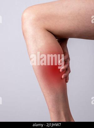 Donna che soffre di dolore muscolare del vitello. Gamba di tenuta con punto rosso primo piano. Stress muscolare, colonna vertebrale, malattie delle vene. Concetto di problemi di salute. Foto di alta qualità Foto Stock