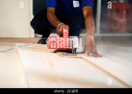 Tiro stretto di carpentiere o di lavoro di legno che taglia il legno usando la macchina circolare della sega sul posto di lavoro - concetto di lavorazione del legno duro, di rinnovamento e di esperto Foto Stock