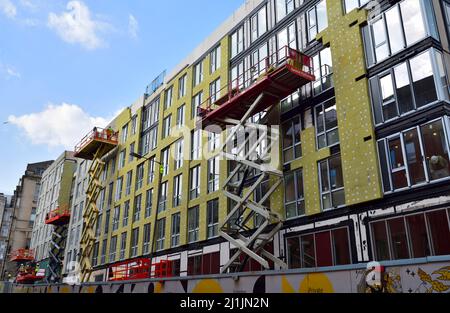 Pannello isolante esterno in lana di roccia installato sulla facciata del nuovo edificio da una piattaforma di sollevamento a forbice prima di rendere acrilico con rinforzo in rete Foto Stock