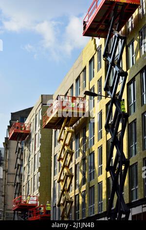 Pannello isolante esterno in lana di roccia che viene installato sulla facciata di un nuovo edificio da una piattaforma di sollevamento a forbice prima di rendere acrilico con rinforzo a rete Foto Stock