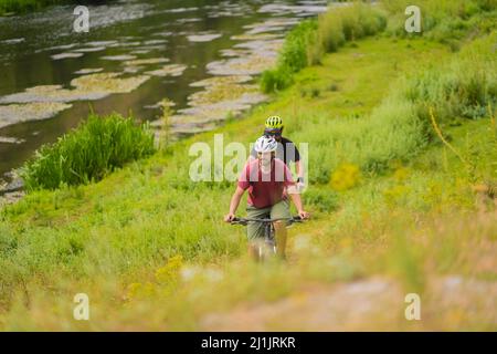 Due maschi in forma stanno guidando le loro biciclette insieme mentre cercano di tenere il passo con il loro gruppo Foto Stock