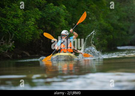 Due adulti in forma e belli sono in canoa per i loro amici mentre cercano di tenere il passo Foto Stock