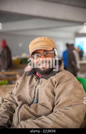 Ritratto di un uomo sorridente con occhiali e telefono cellulare al mercato del pesce, Nouakchott, Mauritania Foto Stock