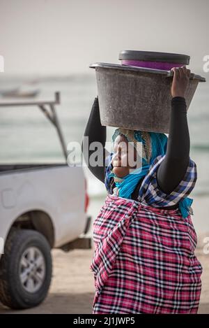 Una donna nera che porta grandi bacini sulla sua testa, Nouakchott mercato del pesce, Mauritania Foto Stock