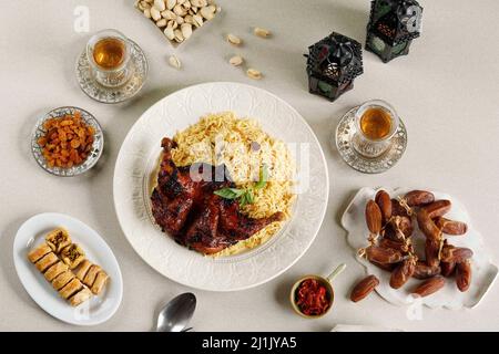 Menu a buffet di Iftar Ramadan, Kabsa di riso Basmati con pollo arrosto, raisina, tè, frutta datteri, pistacchio, E Baklava turco Foto Stock