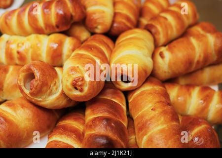 Primo piano con dolci freschi e dorati di salsiccia e pasta sfoglia. Hotdog o salsiccia nell'impasto. Sfondo. Foto Stock