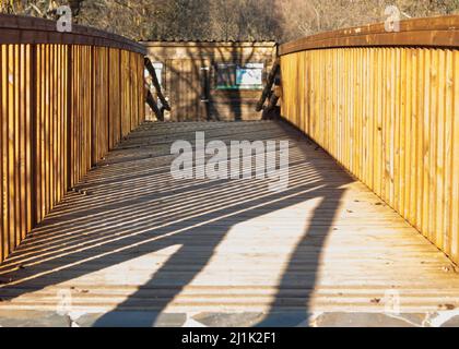 Ombre su passerella in legno con ringhiera in legno che formano scatole diagonali orizzontali Foto Stock