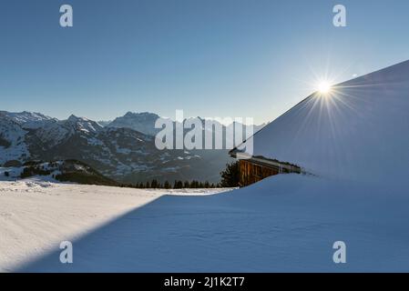 Rifugio alpino coperto di neve di fronte al panorama delle Alpi Glaronesi al sole mattutino, Canton Sankt Gallen, Svizzera Foto Stock