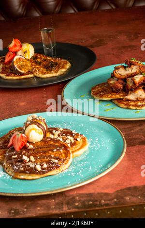Una dose verticale di gustosi pancake al cioccolato serviti con gelato alla vaniglia, noci e frutti di bosco diversi Foto Stock