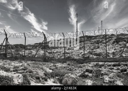 Base militare con recinzione spinato e antenne. Bianco e nero. Foto Stock