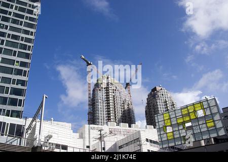 L'Aia, Paesi Bassi - 25 febbraio 2022: Grande torre residenziale in costruzione con due grandi gru gialle in cima Foto Stock