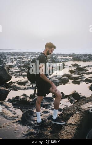 Giovane uomo che usa il cellulare su una spiaggia Foto Stock