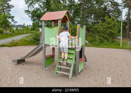 Bella vista di ragazzi scalate su scivolo al parco giochi nella soleggiata giornata estiva. Svezia. Foto Stock