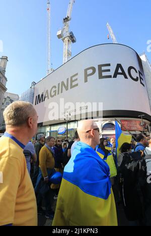 Londra, Regno Unito. 26th marzo 2022. Migliaia di persone si sono unite a una marcia a sostegno dell'Ucraina sabato, mentre il sindaco Sadiq Khan ha esortato il Regno Unito a fare molto di più per aiutare gli Ukainiani. La marcia passò attraverso Piccadilly Circus dove fu esposta la famosa frase di Yoko Ono 'Imagine Peace'. Credit : Monica Wells/Alamy Live News Foto Stock