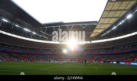 Il sole di tarda serata brilla attraverso le finestre in cima allo stadio mentre i giocatori inglesi prendono parte al riscaldamento prima della partita internazionale della Alzheimer's Society al Wembley Stadium di Londra. Data foto: Sabato 26 marzo 2022. Foto Stock