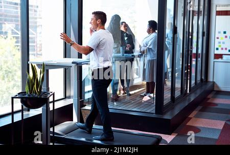 I theres non devono essere deskbound come capo al successo. Shot di un giovane uomo d'affari che parla su un cellulare e che passa attraverso il lavoro di carta mentre si cammina su Foto Stock