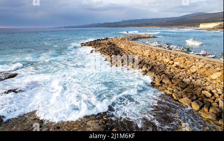 Vista aerea del drone delle barche da pesca ormeggiate al porto a frangiflutti. Onde tempestose in mare Foto Stock