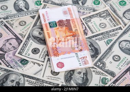 Un pacchetto di soldi russi che giacciono sui dollari statunitensi Foto Stock