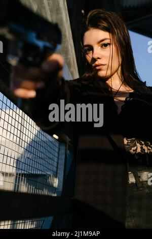 giovane donna con una pistola pronta a sparare Foto Stock