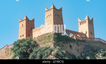 Un castello di pietra di colore chiaro sulla cima di una collina con torrette e arcate e un muro che circonda l'esterno Foto Stock